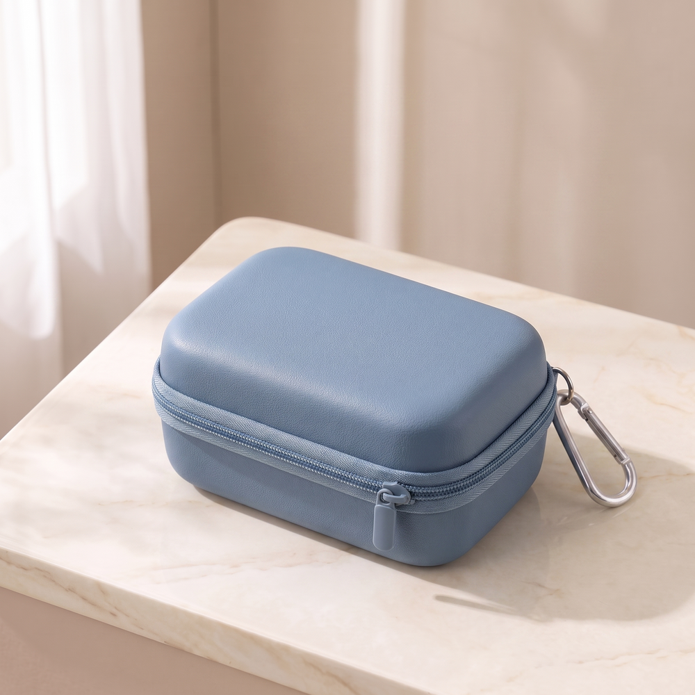 Blue hard shell camera case, closed, on cream marble with its carabiner clip