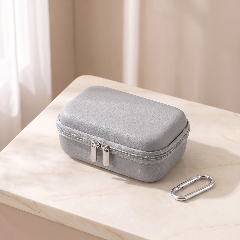 Grey hard shell camera case, closed, on cream marble with its carabiner clip