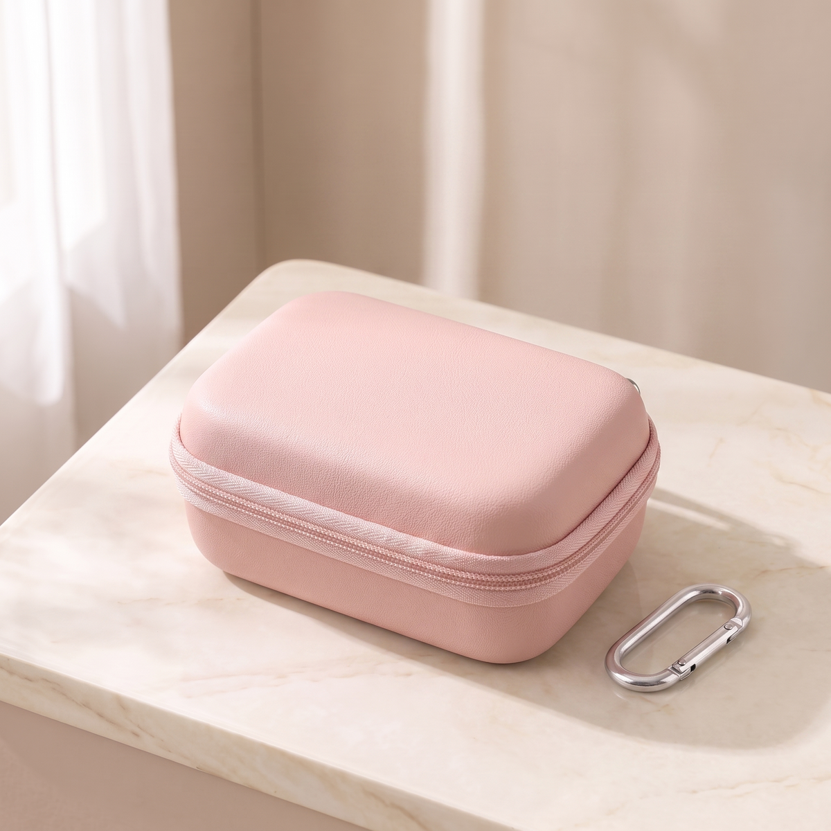 Pink hard shell camera case, closed, on cream marble with its carabiner clip
